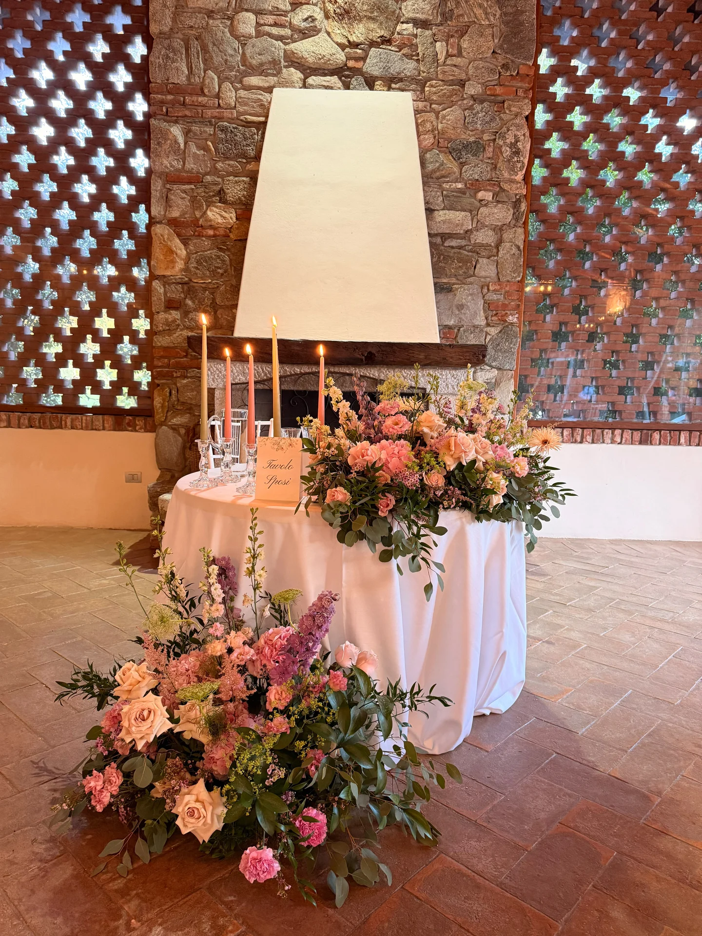 Tavolo della cerimonia con candele e composizioni floreali rosa