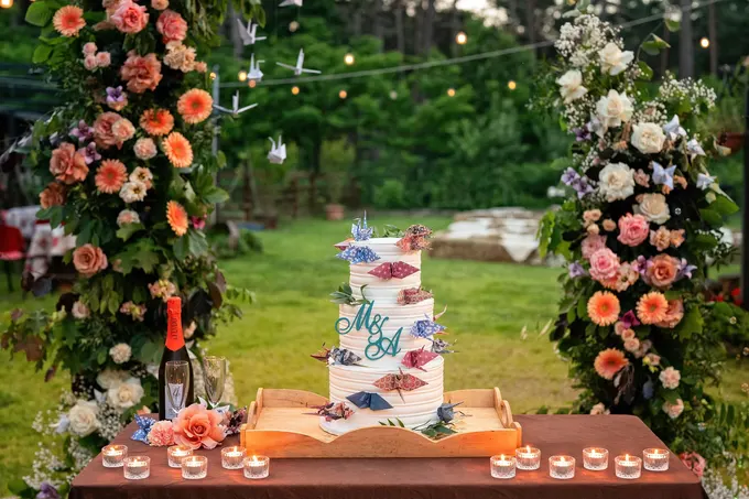 Torta nuziale a più piani fra colonne di fiori all’aperto