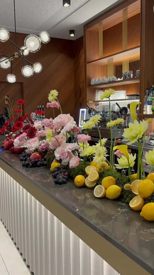 Fiori rosa, bianchi e gialli con limoni su un bancone