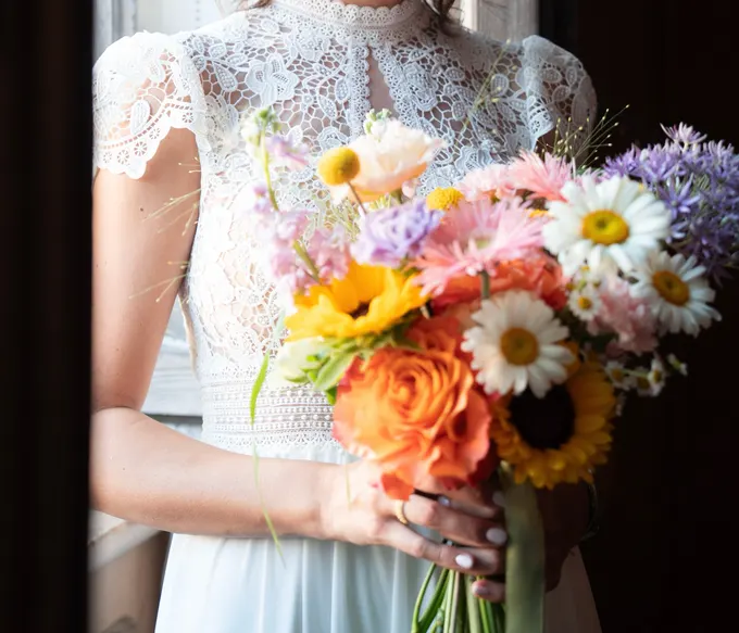 Bouquet arancione, giallo, rosa e bianco tra le mani