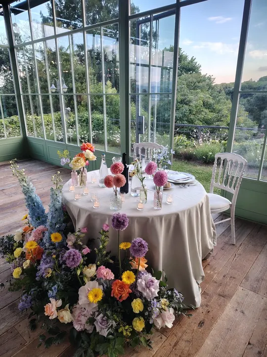 Tavolo del ricevimento con fiori colorati e candele davanti alla vetrata